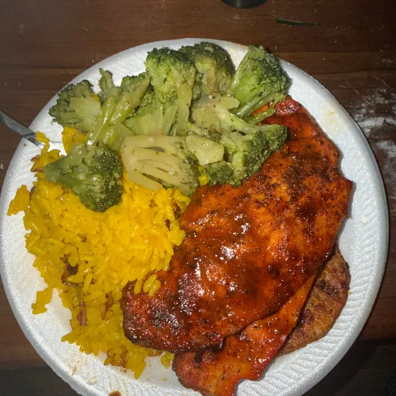 Barbecue chicken over yellow rice with broccoli and cauliflower.