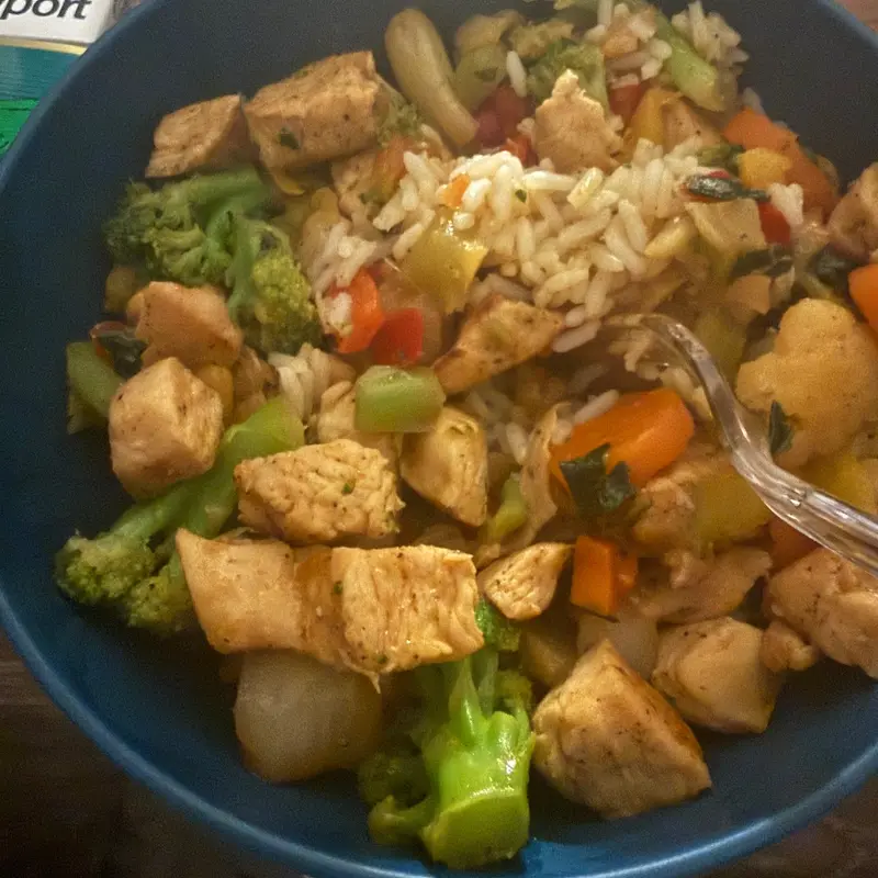Chicken stir fry with broccoli, carrots and peppers over rice.