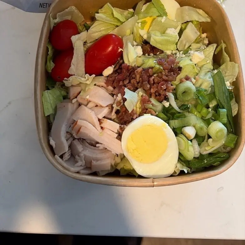 Cobb salad with turkey, bacon, egg, tomato and spring onion.