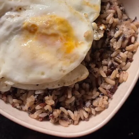 Fried eggs over a bowl of wild rice.