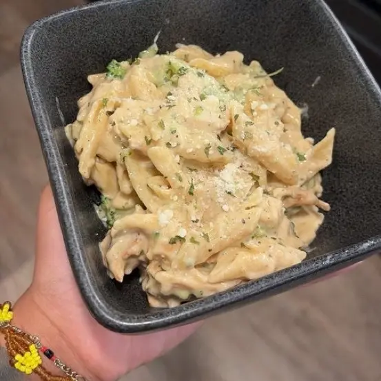 Pasta in a cream sauce with broccoli and grated cheese.