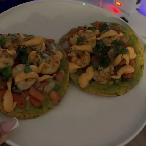 Shrimp tostadas with guacamole and chopped tomato.